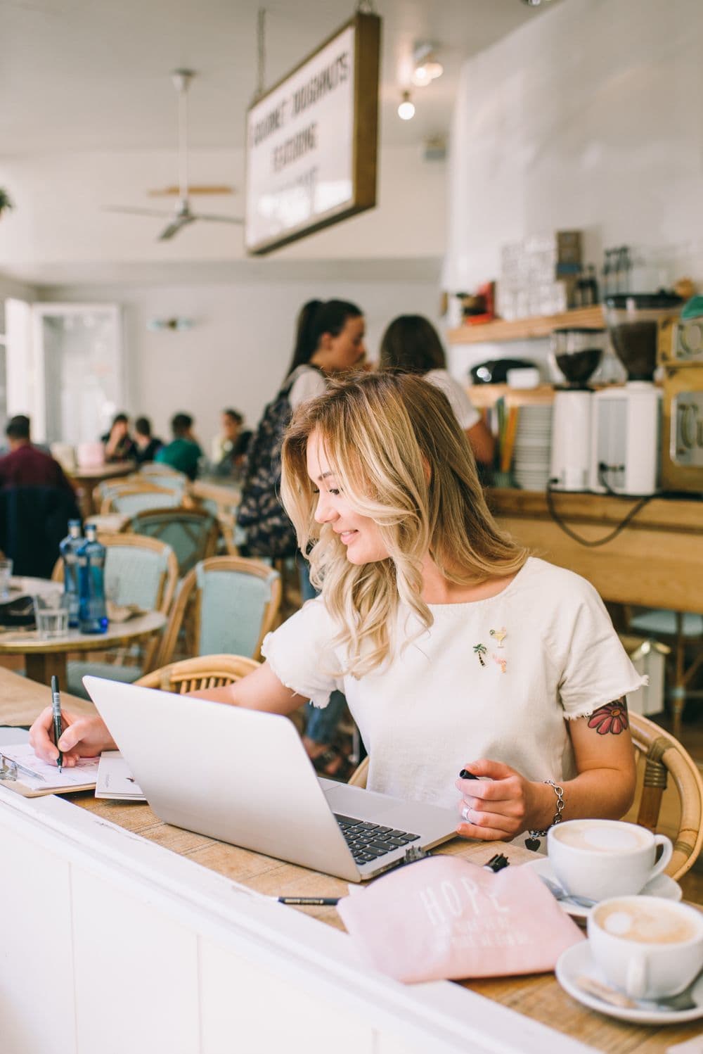 A business owner working on a laptop with a coffee in a bright cafe
