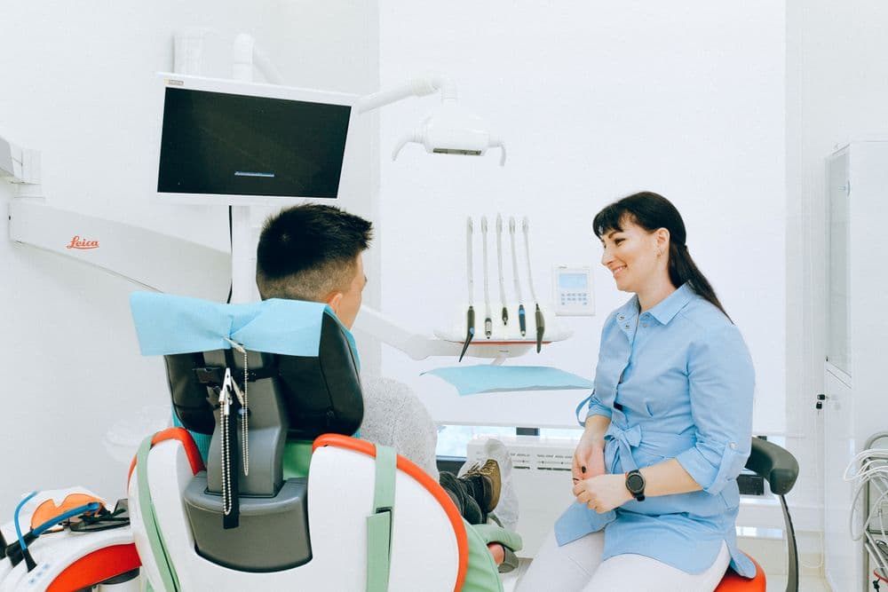 A smiling dentist talking with a patient in a bright dental clinic