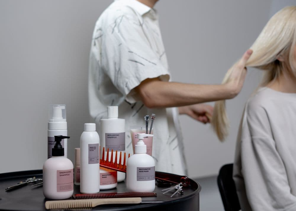 A hairdresser styling a client's long blonde hair in a salon